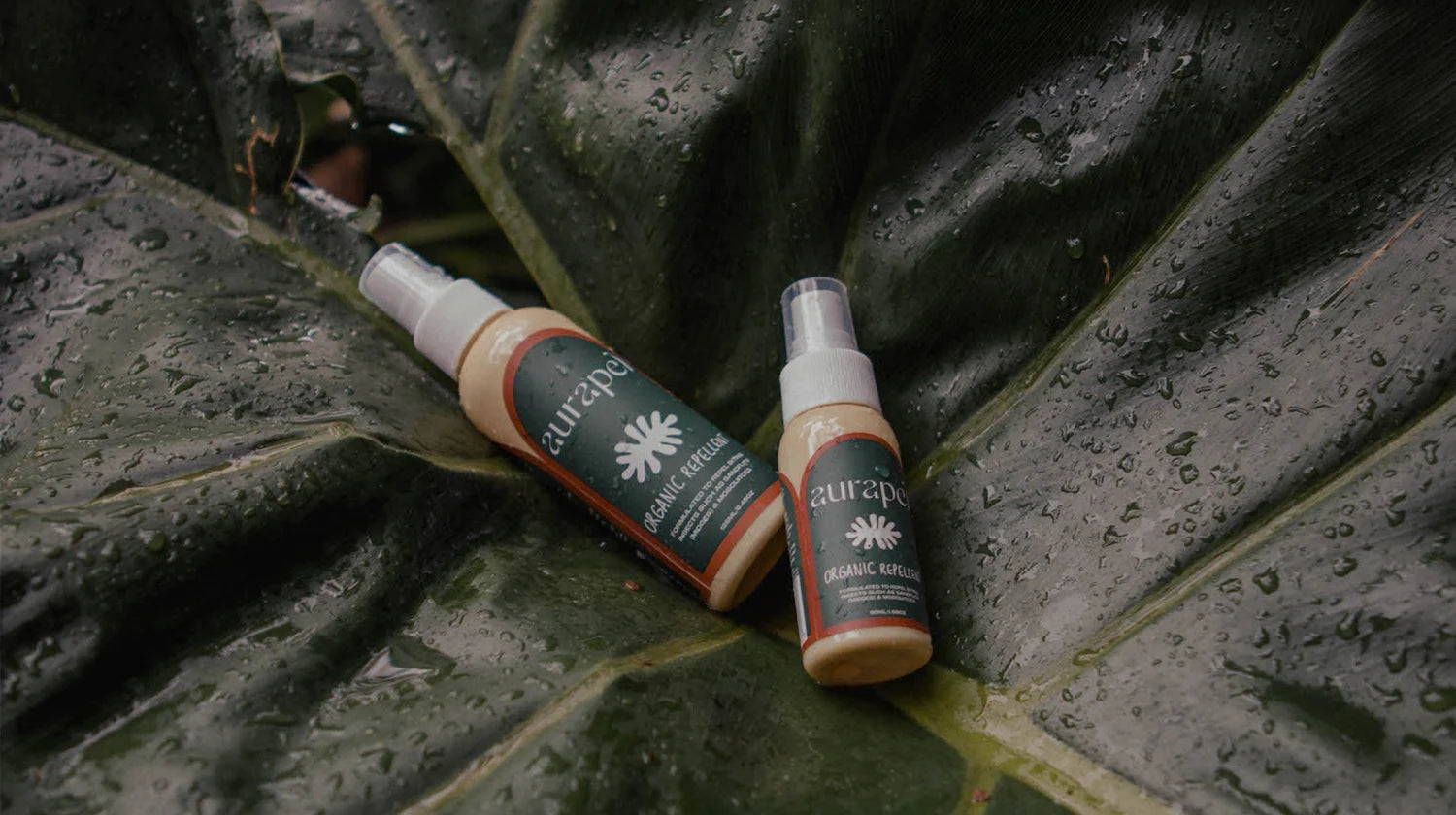 Aurapel natural insect repellant product on dewy dark green leaves