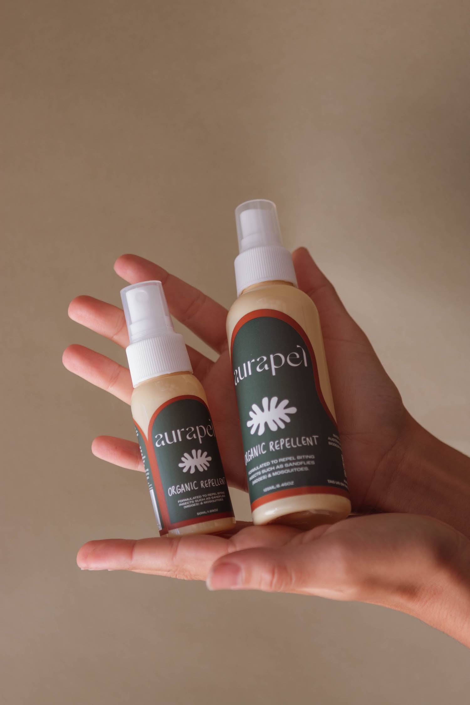 Hands holding 50ml and 125ml Aurapel bottles